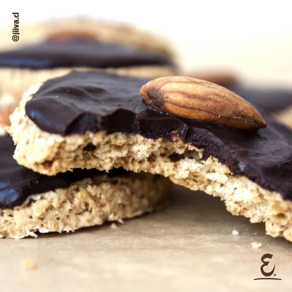 Galletas caseras saludables de avena y almendras cubiertas con chocolate amargo y una almendra entera, preparadas con huevos de gallinas libres a pastoreo Ecoterra.