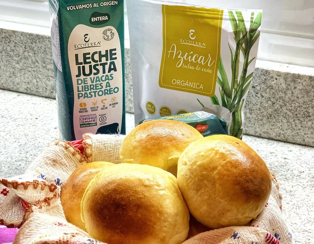 Mesa de cocina con panes brioche dorados hechos con técnica Tang Zhong junto a envases de Leche Entera de vacas libres a pastoreo y Azúcar Rubia Orgánica Ecoterra